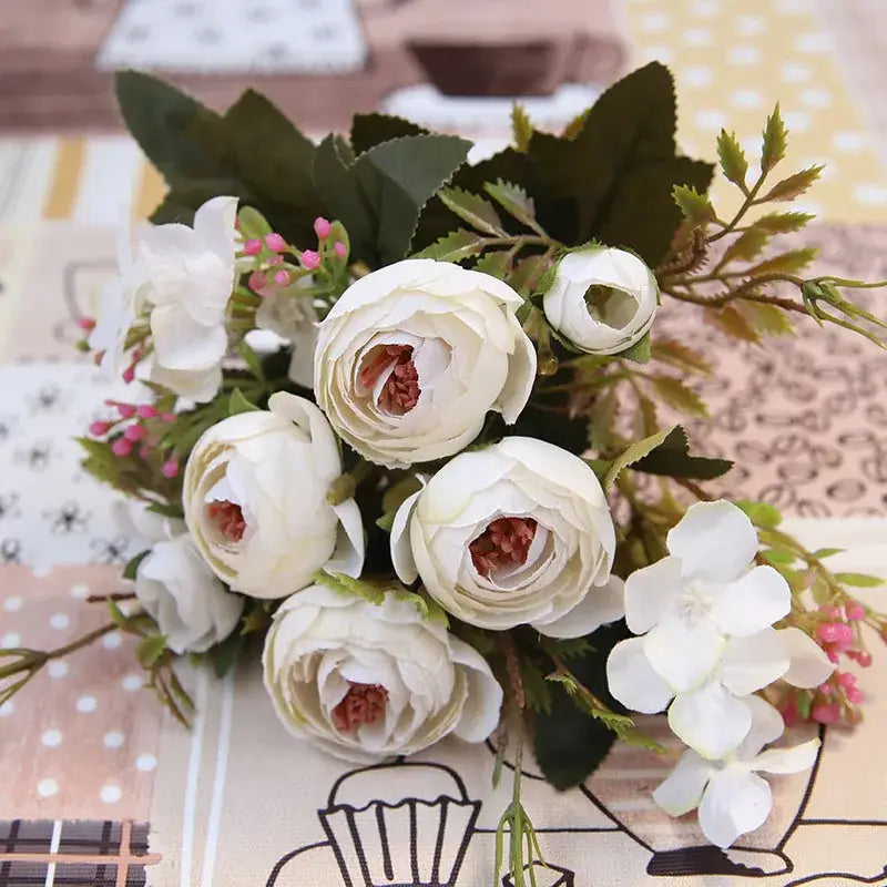 A delicate silk tea rose ranunculus bouquet in white and pink with green foliage for wedding decor