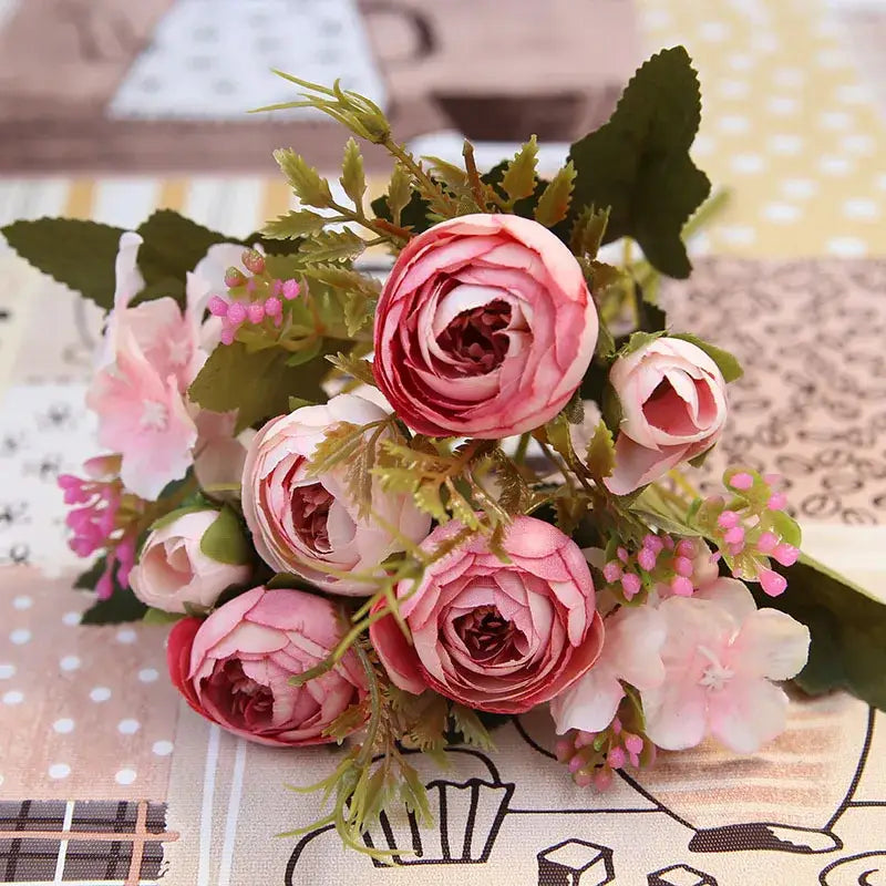 A delicate pink and white silk tea rose ranunculus bouquet with green foliage for wedding decor and autumn silk tea themes