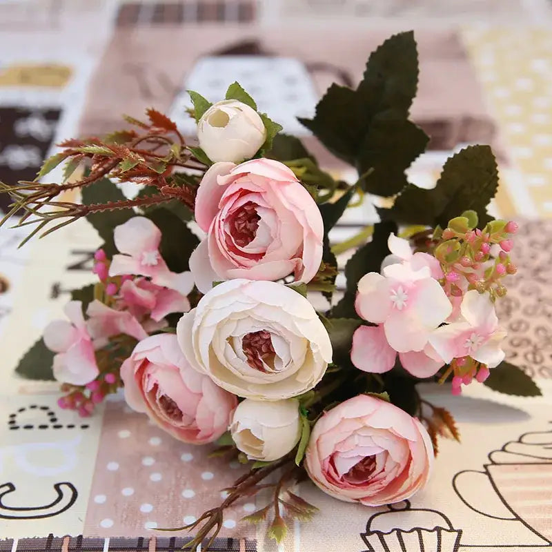 A delicate silk tea rose ranunculus bouquet in pink and white with green leaves for wedding decor