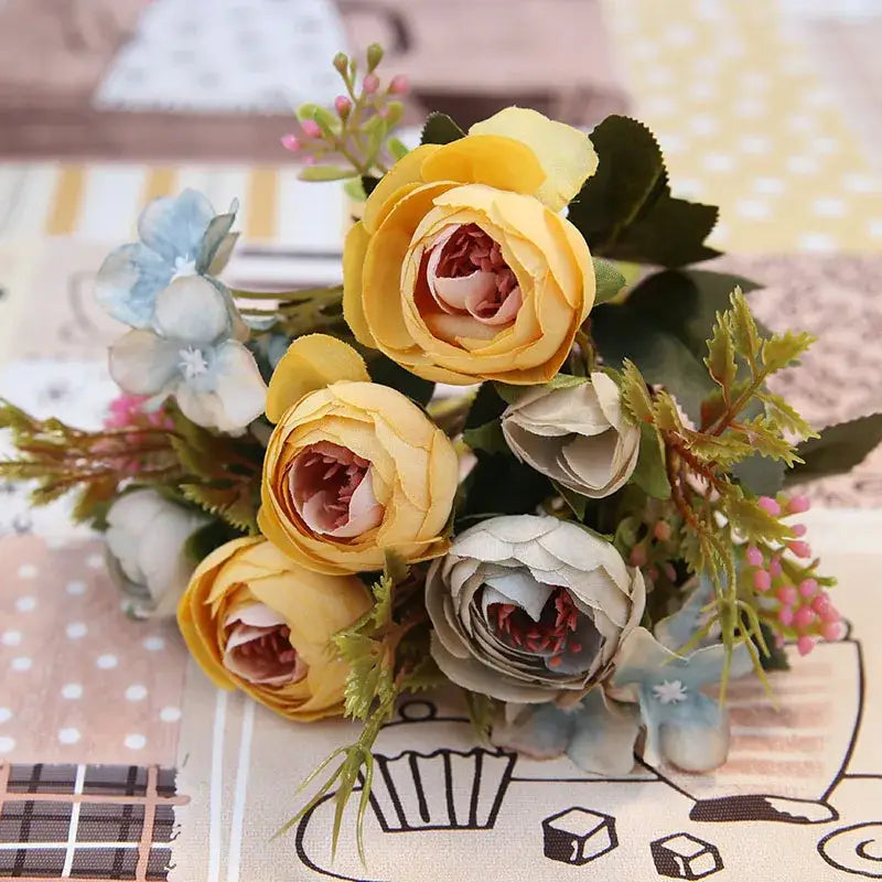 A delicate silk tea rose bouquet with soft yellow and pale blue roses and pink buds for wedding decor