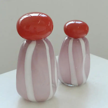 Two translucent glass cactus figurines with pink and white stripes and red caps complement a vase cover band decor