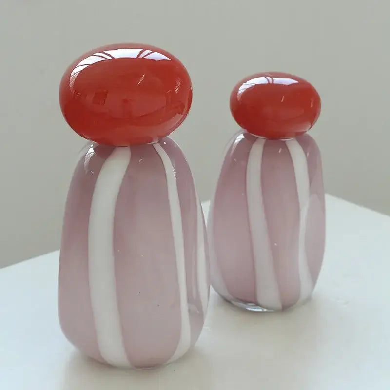 Two translucent glass cactus figurines with pink and white stripes and red caps complement a vase cover band decor