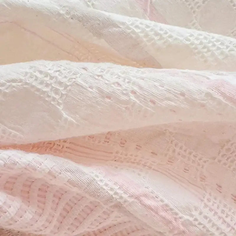 Delicate white lace fabric with pink undertones on pink and white striped jacquard cotton bedding set by decorbites