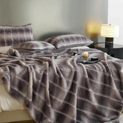 Soft gray faux fur throw blanket with subtle stripes draped over bed from decorbites cozy fleece collection