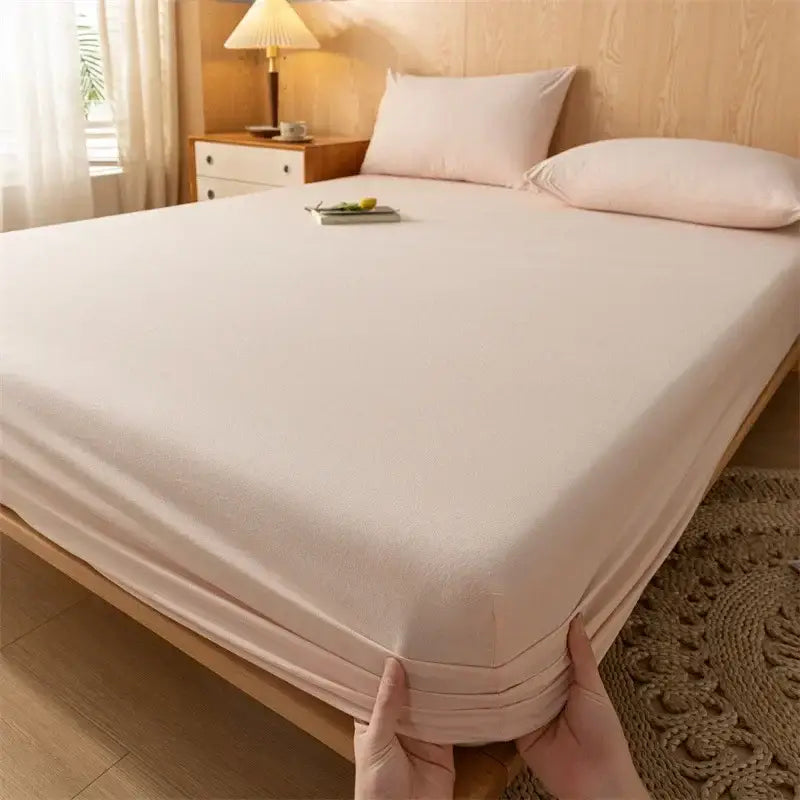 Soft pale pink cotton fitted sheet with smooth texture and elastic edge paired with plaid green beige cotton fitted sheet decorbites