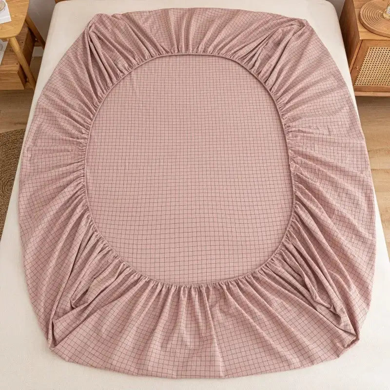 A soft pink decorbites cotton fitted sheet with subtle grid pattern and stretchy fabric for snug mattress fit