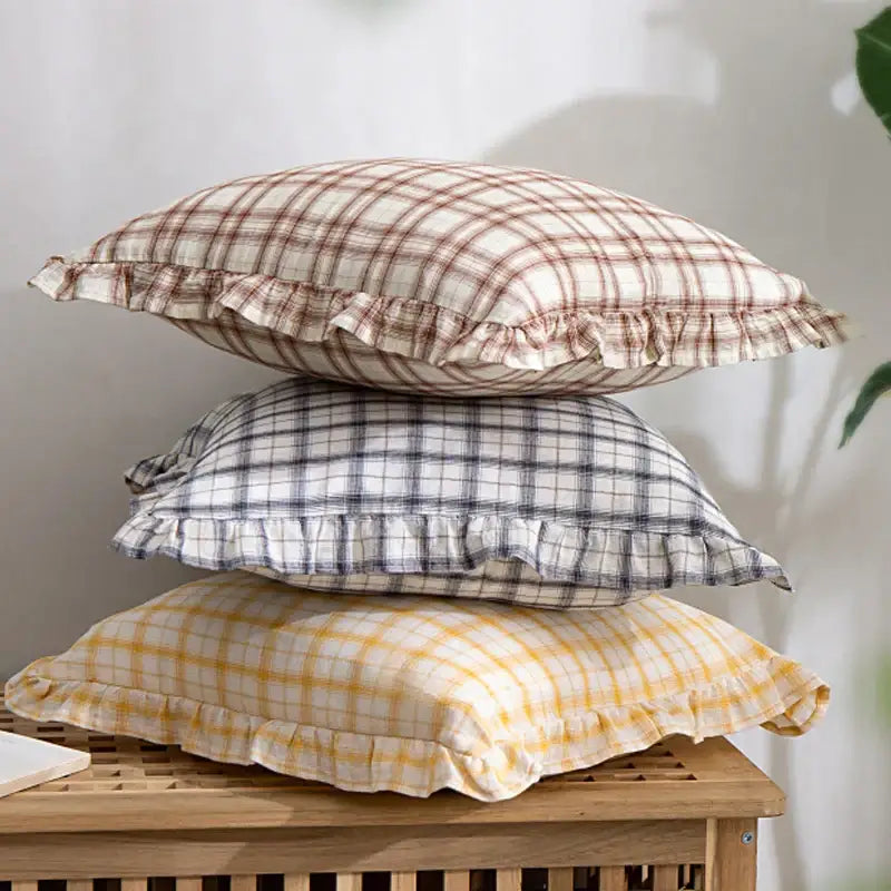 Stacked cotton coffee black cushion covers with plaid patterns and ruffled edges on a wooden surface for living room decor