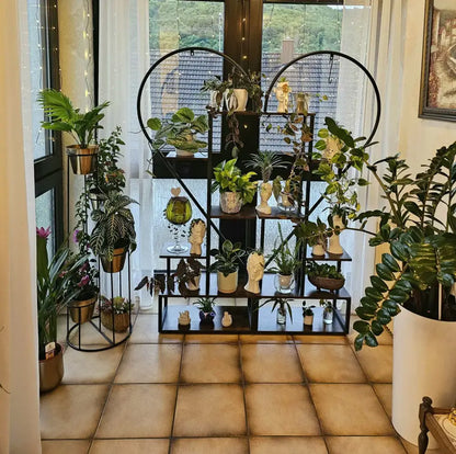 Black metal heart shaped plant display stand with six tiers holding potted plants and decorative figurines by decorbites