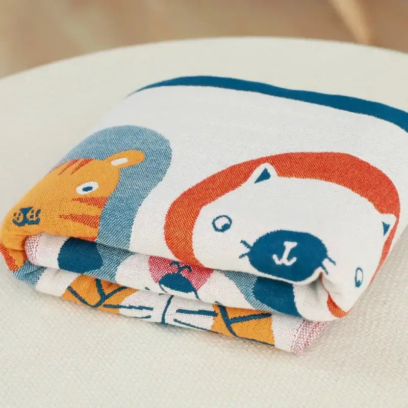Folded soft cotton bath towel with playful orange and blue cartoon lions on white decorbites lions bath design
