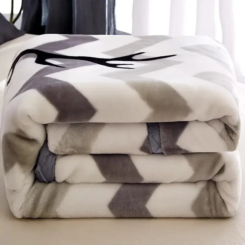 A plush black and white chevron winter raschel blanket with a gray and white geometric pattern and a black deer antler design