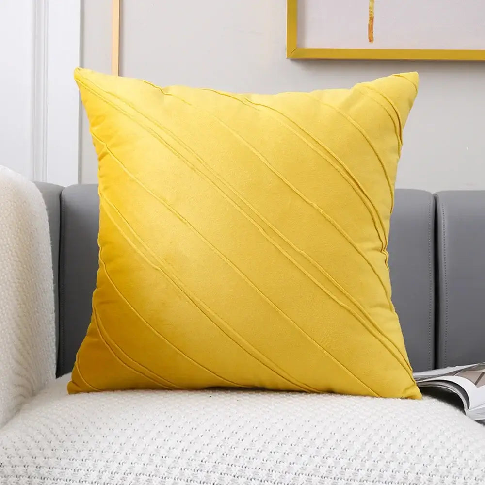 Vibrant yellow velvet throw pillow with diagonal pleated design next to plush black and white decorbites houndstooth cushion cover