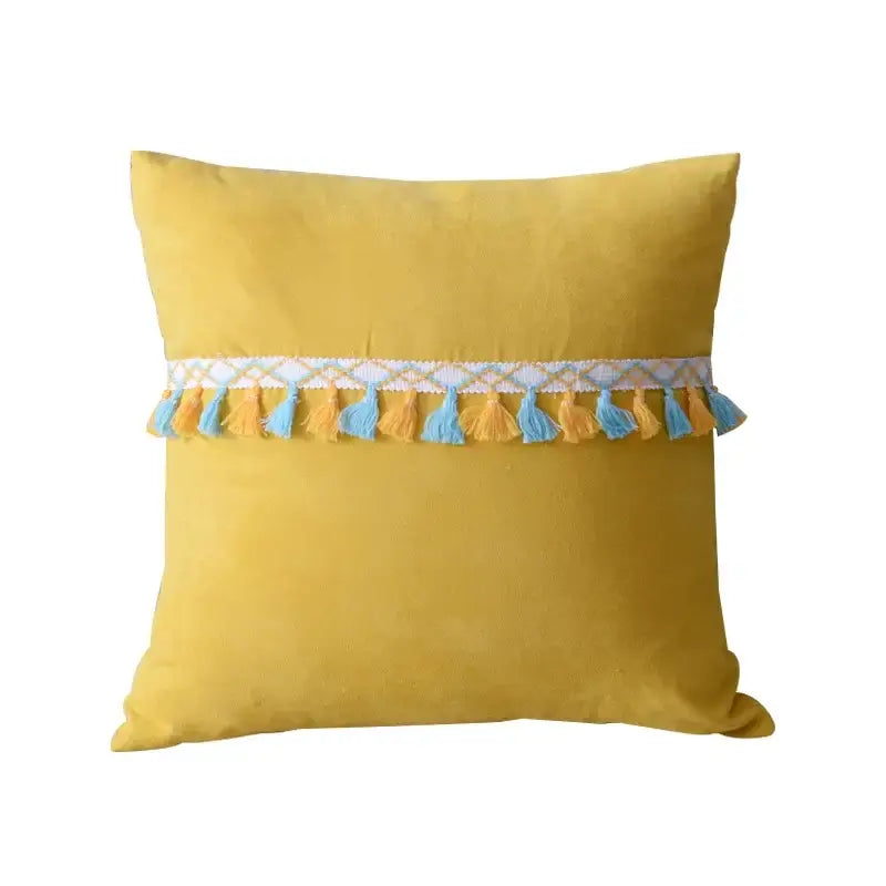 A square yellow velvet pillow with a decorative band of blue and mustard tassels paired with decorbites houndstooth cushion cover