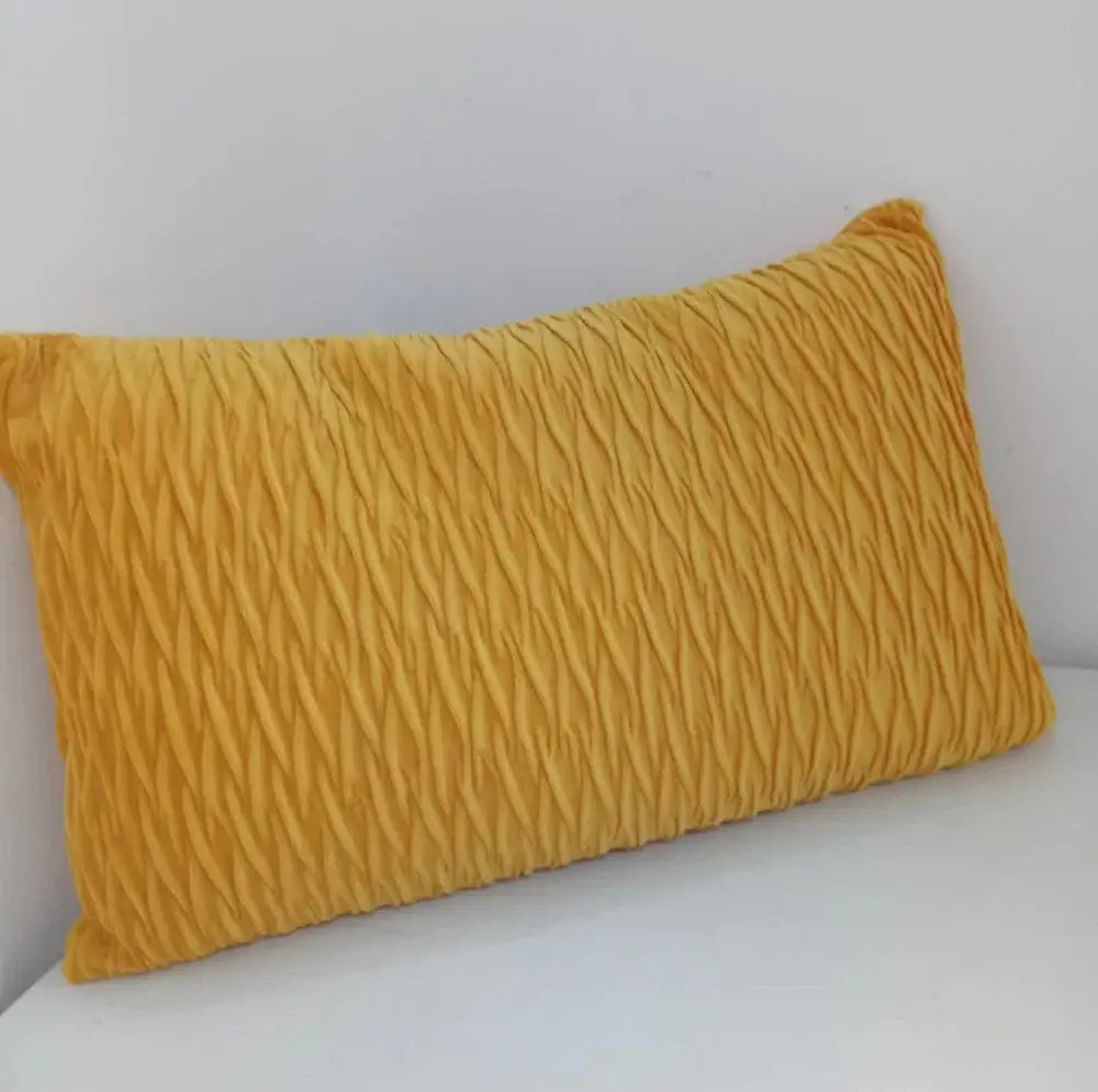 A mustard-yellow rectangular pillow with textured pleated fabric beside a plush black and white houndstooth cushion cover
