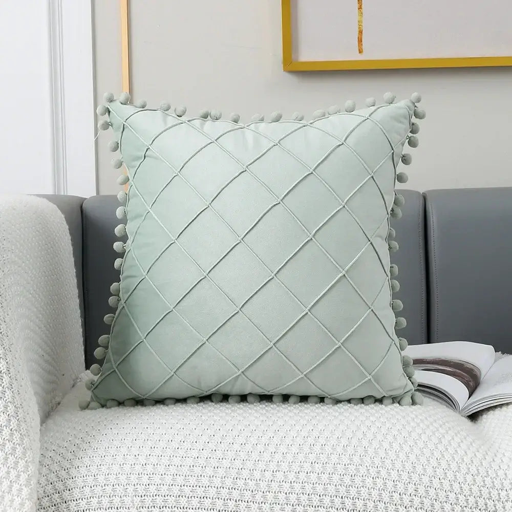 Light green quilted pillow with diamond pattern and gray pom-pom trim as part of decorbites houndstooth cushion cover collection