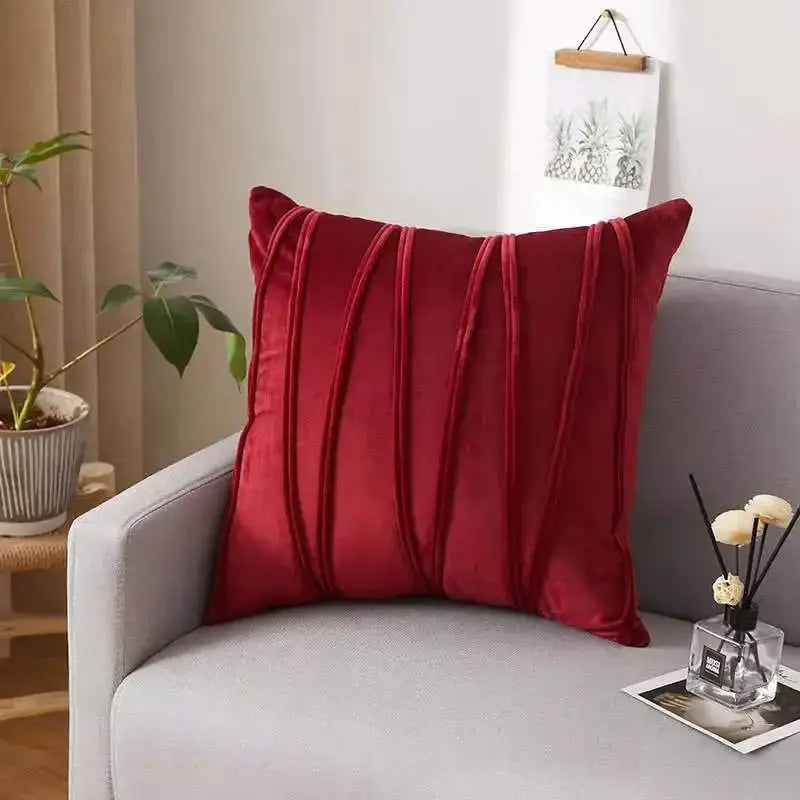 A plush deep red velvet throw pillow with vertical pleated detailing on a gray sofa contrasting with decorbites houndstooth cushion cover