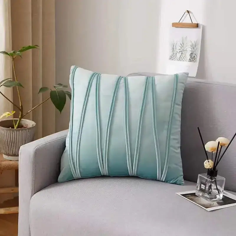 A soft mint green velvet throw pillow with vertical pleats on a gray sofa next to a plush black and white decorbites houndstooth cushion cover