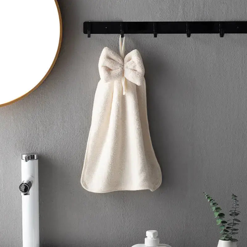 Cream-colored plush coral velvet soft hand towels with large bow hanging on black rack ideal for kitchen and bathroom decorbites coral velvet