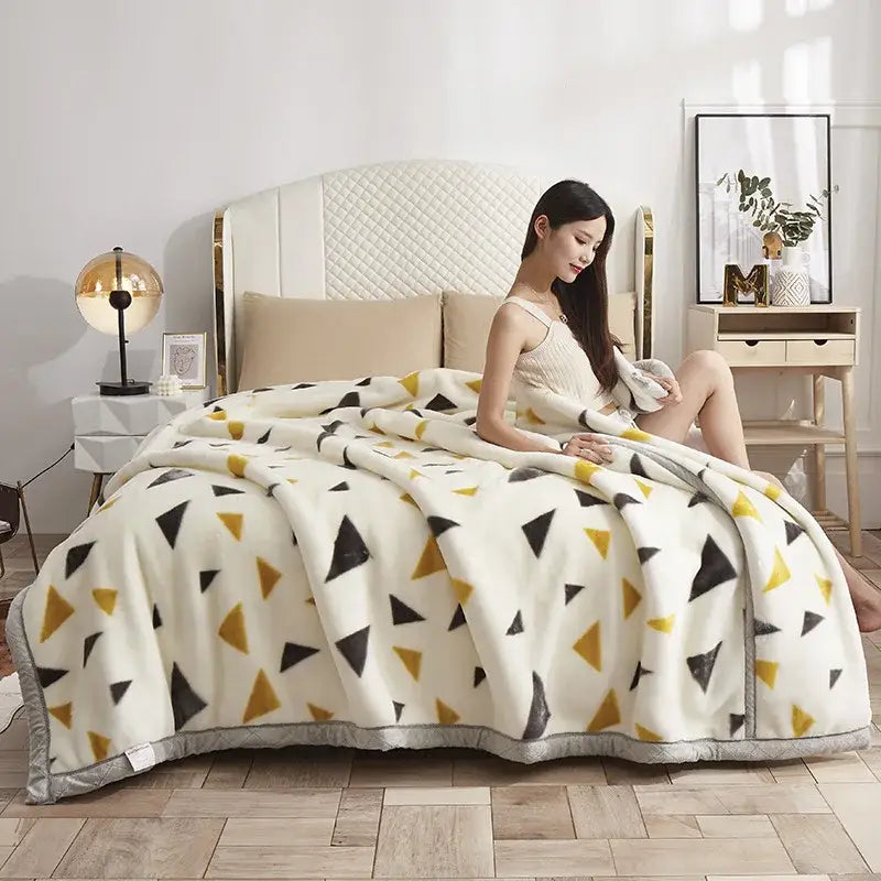A cozy cream double layer raschel fleece throw blanket with black and mustard-yellow triangles and a gray border
