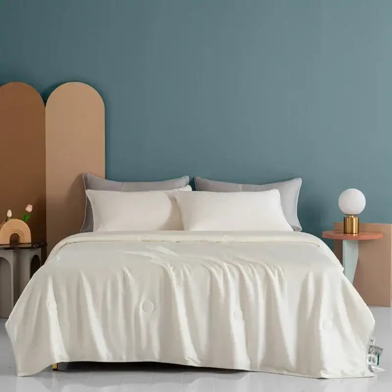 Cream-colored satin decorbites cooling comforter with subtle sheen and soft flowing drape for plush bedroom decor