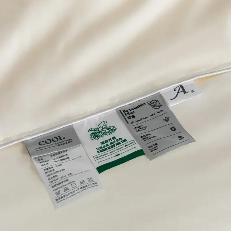 Cream-colored satin cooling comforter with stitched care labels for decorbites cooling comforter bedroom use