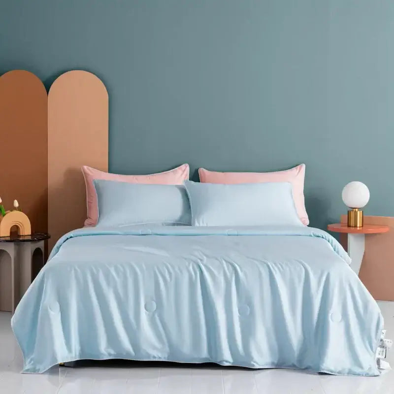 Light blue satin decorbites cooling comforter with subtle quilted stitching and matching pillowcases in soft pastel tones