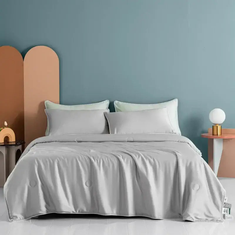 A soft light gray satin decorbites cooling comforter with subtle quilted stitching and silky smooth texture