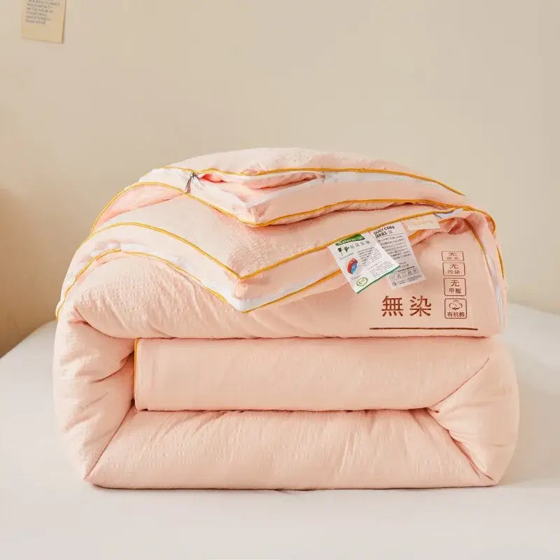 A plush cream cozy soy fiber quilt in soft peach with golden stitching and a tag featuring chinese characters