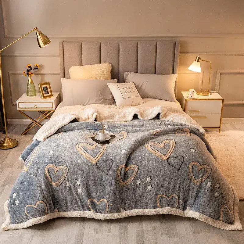 A cozy gray fleece wool blanket with embroidered gold and black hearts and stars and soft white sherpa trim