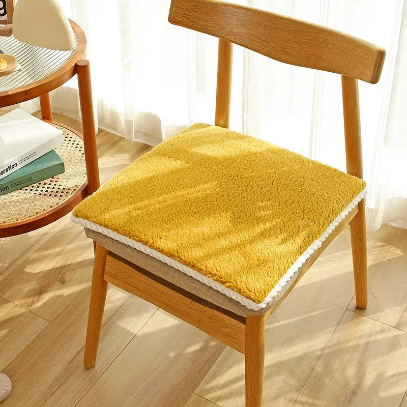 Yellow plush lamb’s wool chair cushion with white crochet trim providing decorbites cozy dining room comfort