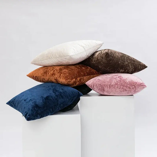 A stack of plush velvet pillow covers in dark grain tones including white brown rust orange navy and dusty pink