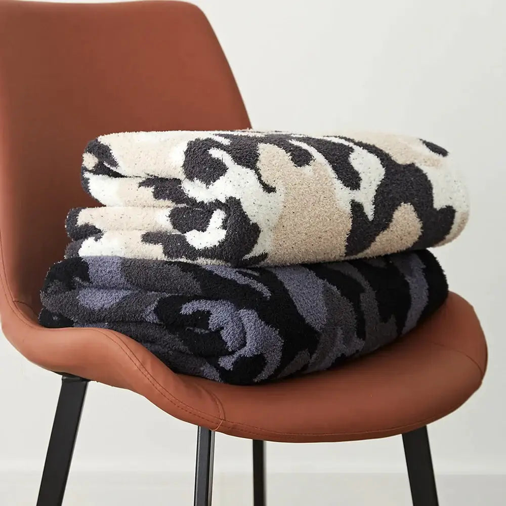 Stacked plush dark gray and black decorbites camouflage knitted throw blankets with soft textured surface for bedroom decor