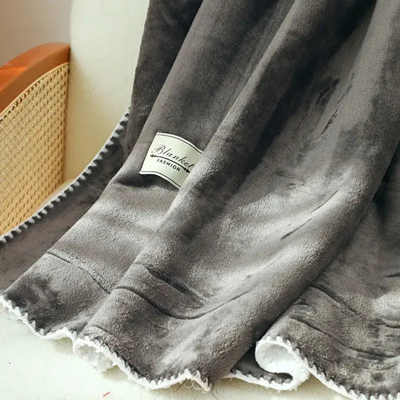 A plush dark gray decorbites double-layer warm blanket with soft velour texture and white frayed edges for cozy use
