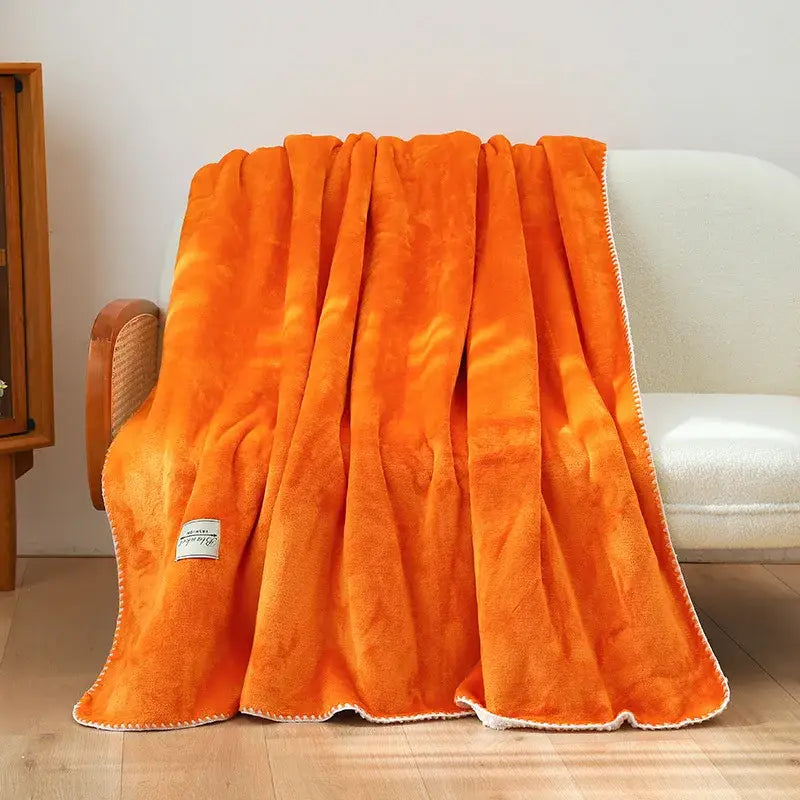 A plush vibrant orange decorbites double-layer warm blanket with soft textured surface and white stitched trim edges