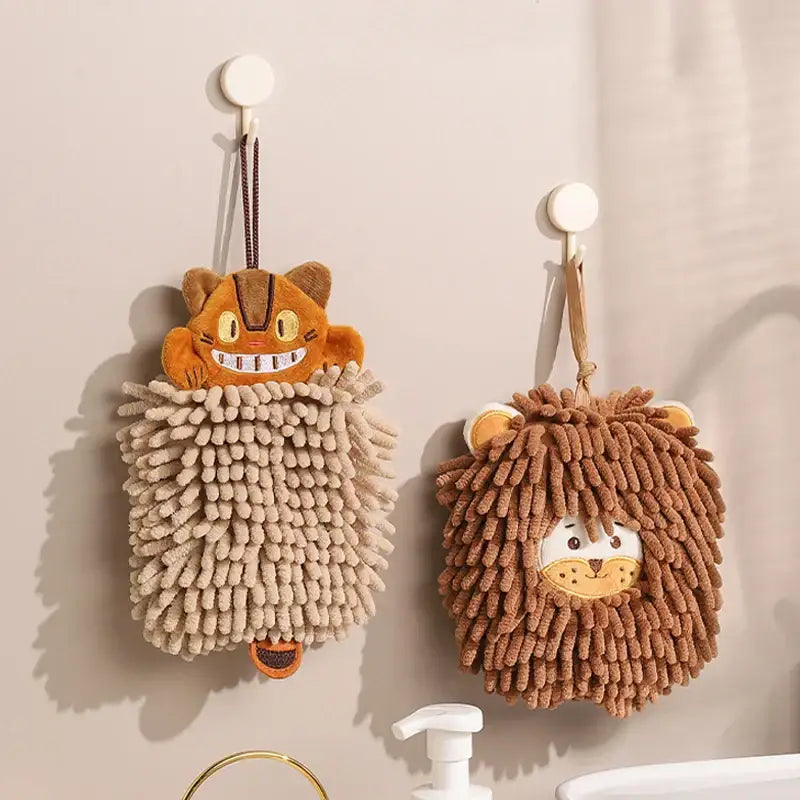Two plush orange and beige microfiber hand towels shaped like a cat and lion hang as decorbites cat kitchen hand towels