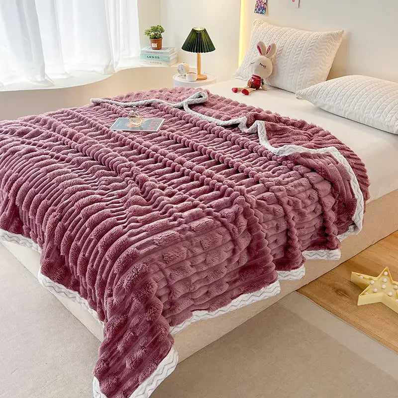 A plush mauve bamboo velvet blanket with ribbed texture and white zigzag-trimmed braided edges for bedroom use