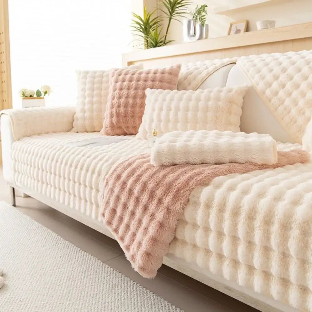 Cream-colored plush quilted sofa slipcover with soft rabbit fur texture and matching pink accents for living room use