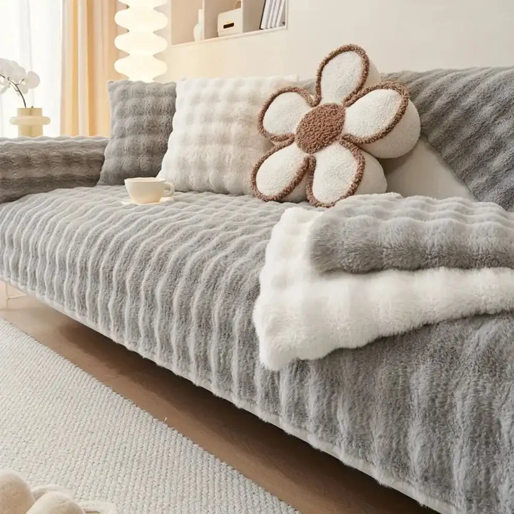 Gray ribbed faux fur sofa cover with plush white and brown flower pillow on plush quilted beige and cream rabbit fur sofa slipcover