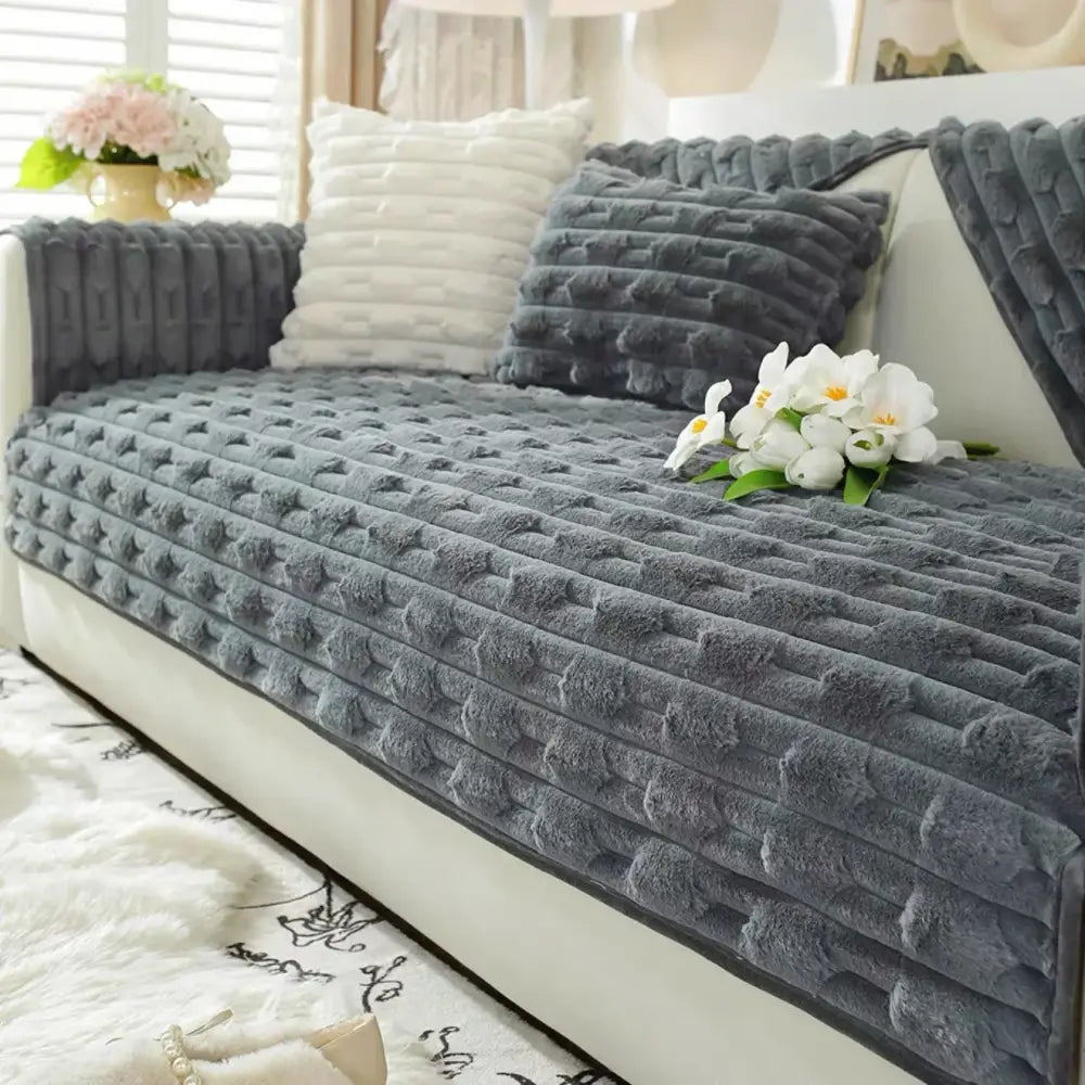 Gray plush cushion cover with textured quilted pattern complementing beige and cream rabbit fur sofa slipcover