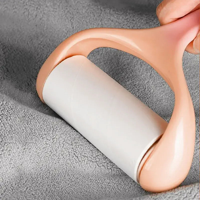 Peach plastic-handled lint roller with white adhesive roll placed on plush white and gray duck terry towel for cleaning