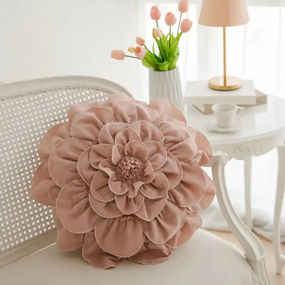 A plush blush pink decorbites 3d flowers pillow with layered fabric petals on a white chair for home decor