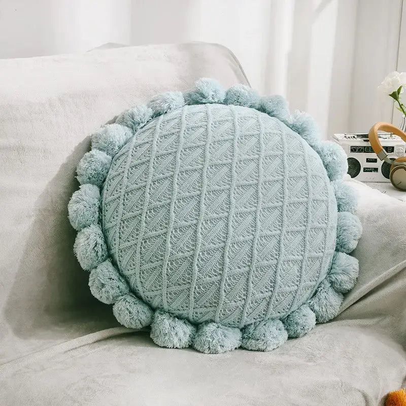 A soft light blue knitted round pillow with fluffy pom-poms complementing plush white and soft pink decorbites 3d flowers pillows for home decor