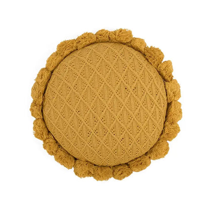 A round mustard-yellow knit cushion with diamond texture and pom-pom trim for home decor or decorbites 3d flowers pillows