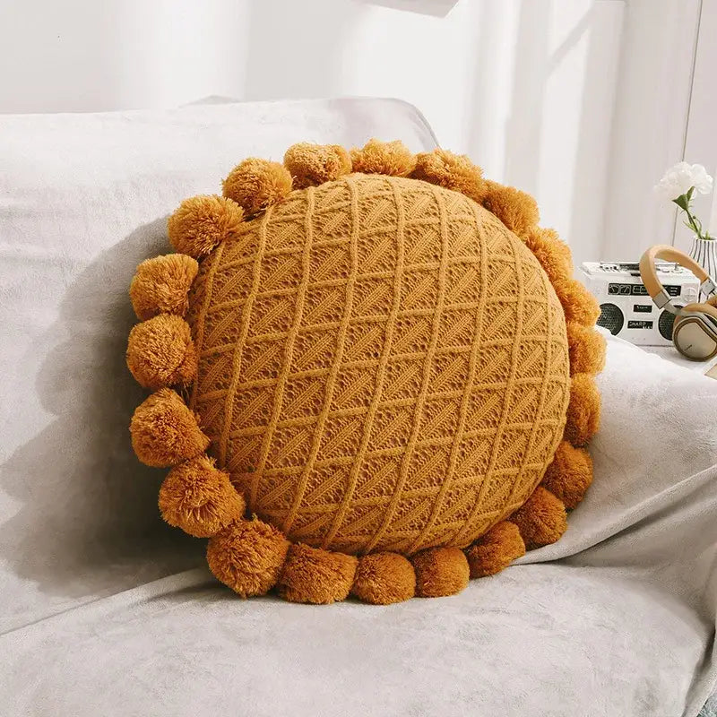 Warm mustard-yellow knitted round pillow with textured diamond pattern and pom-pom trim for home decor flowers pillows decorbites 3d flowers