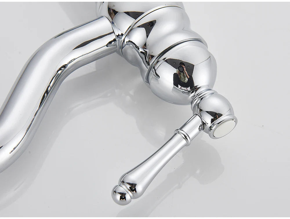 Chrome-finished single hole deck mounted vintage-style kitchen faucet with ornate curved spout and decorative handle housing material