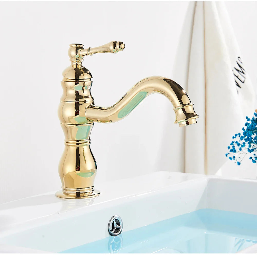 Golden brass-finished deck mounted single hole vintage-style bathroom faucet with ornate detailing and curved spout