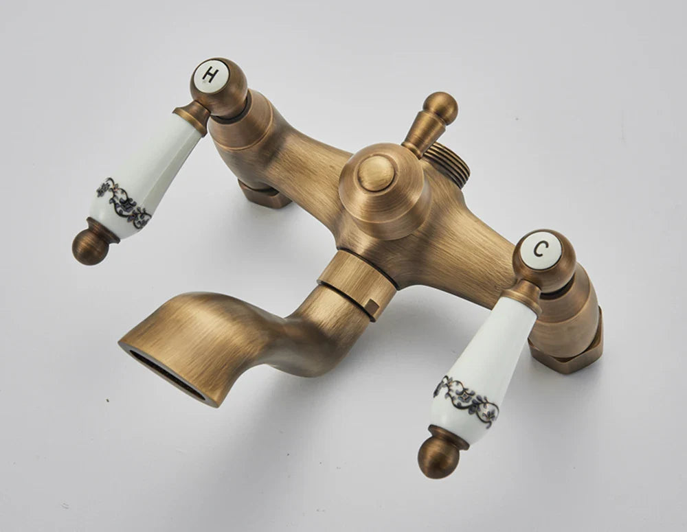 Antique brass-finished dual-handle shower faucet with white ceramic handles featuring black floral patterns and h c labels