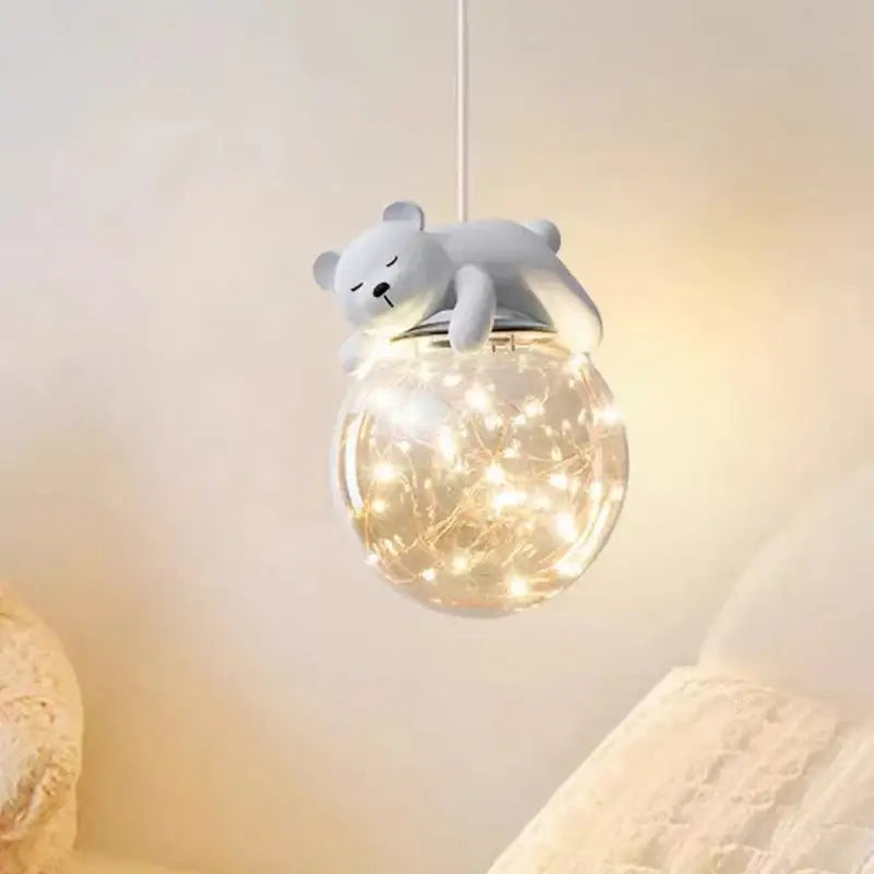 A soft gray plush polar bear perched on a glass animal led chandelier with warm fairy lights for children’s room