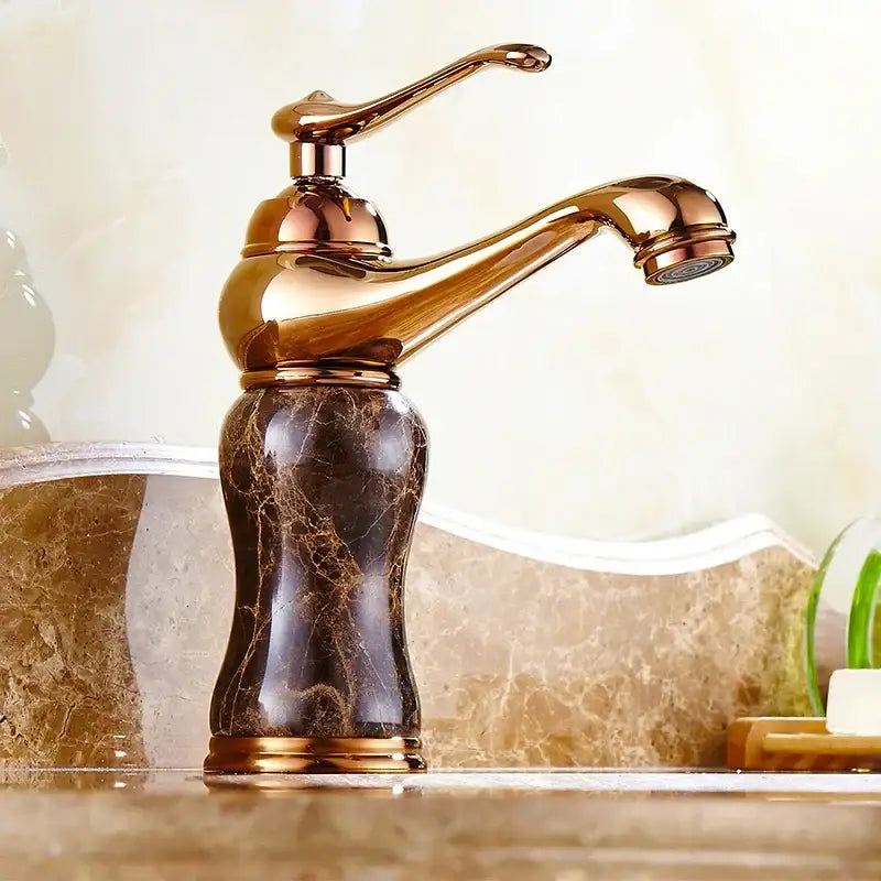 A polished brass bathroom sink faucet with a bronze finish and decorbites golden marble base for golden marble bathroom decor