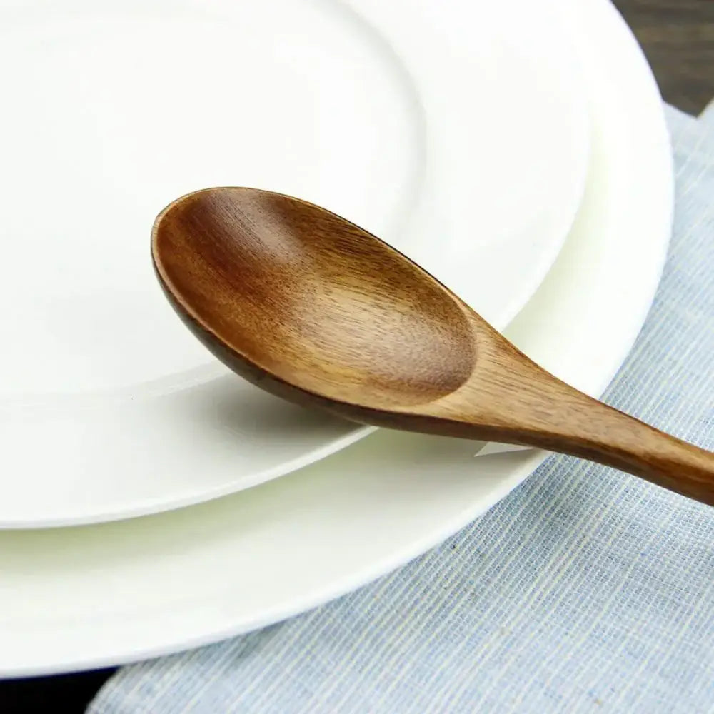 Polished dark brown wooden spoon soup and fork set featuring a smooth medium brown wooden spoon on white plates