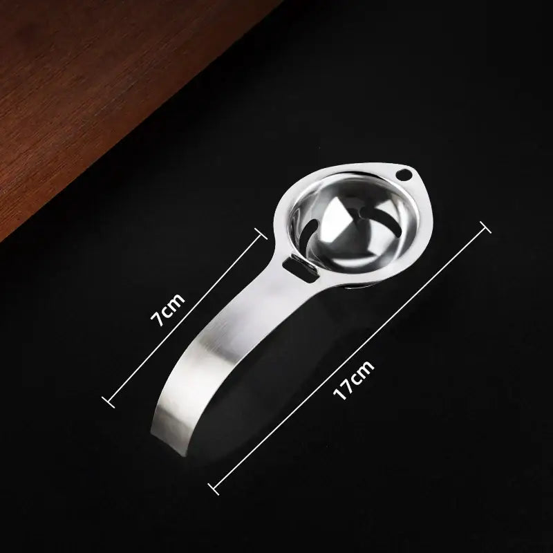 Polished stainless steel egg white separator with a sleek design and curved handle for easy yolk filtering